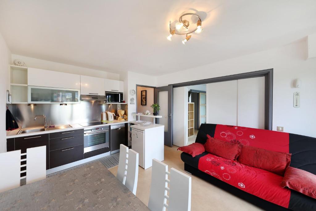 un salon avec un canapé rouge et une cuisine dans l'établissement Les Xettes - Appartement vue montagne, à Gérardmer