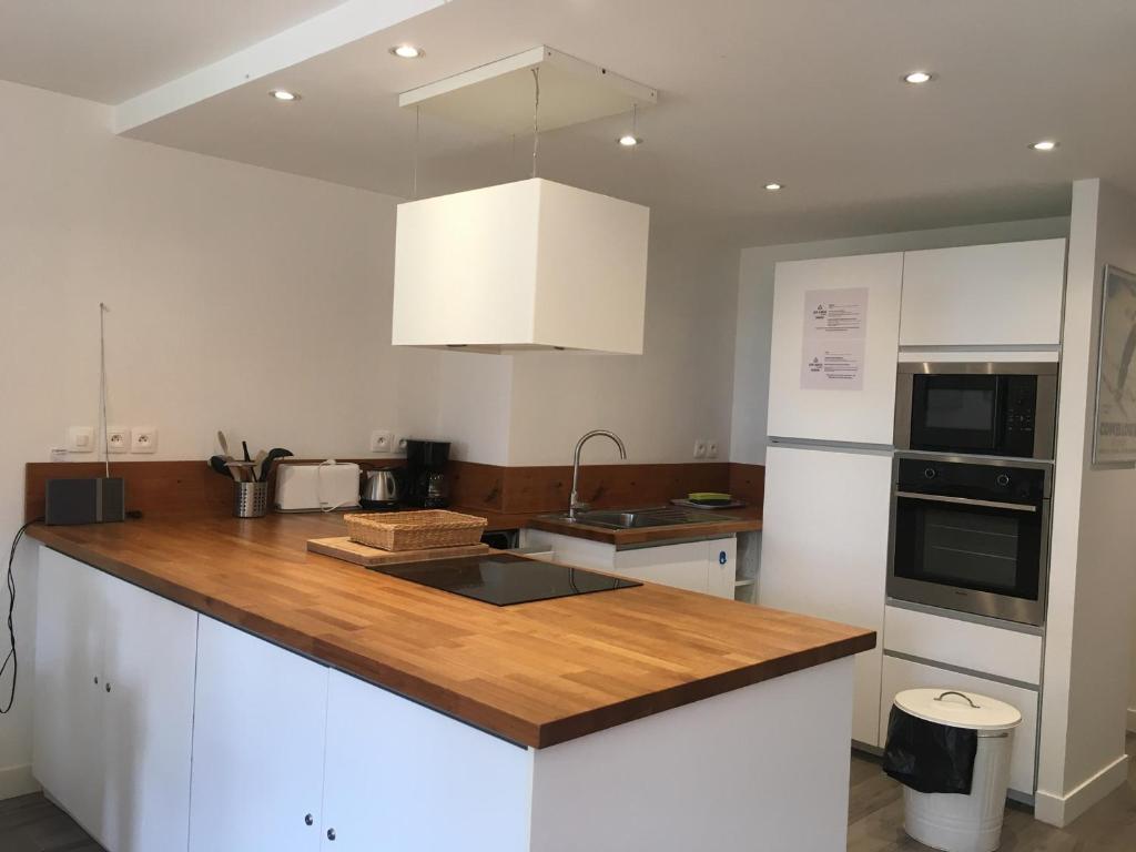 a kitchen with white cabinets and a wooden counter top at Appartement spacieux 8 pers, balcon, centre station - FR-1-346-400 in Arc 1800