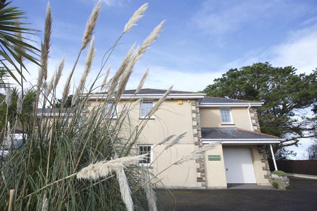 una casa con hierba alta delante de ella en Woodlands, Little Carloggas, St Mawgan, Newquay, Cornwall, TR8 4EQ, en Newquay