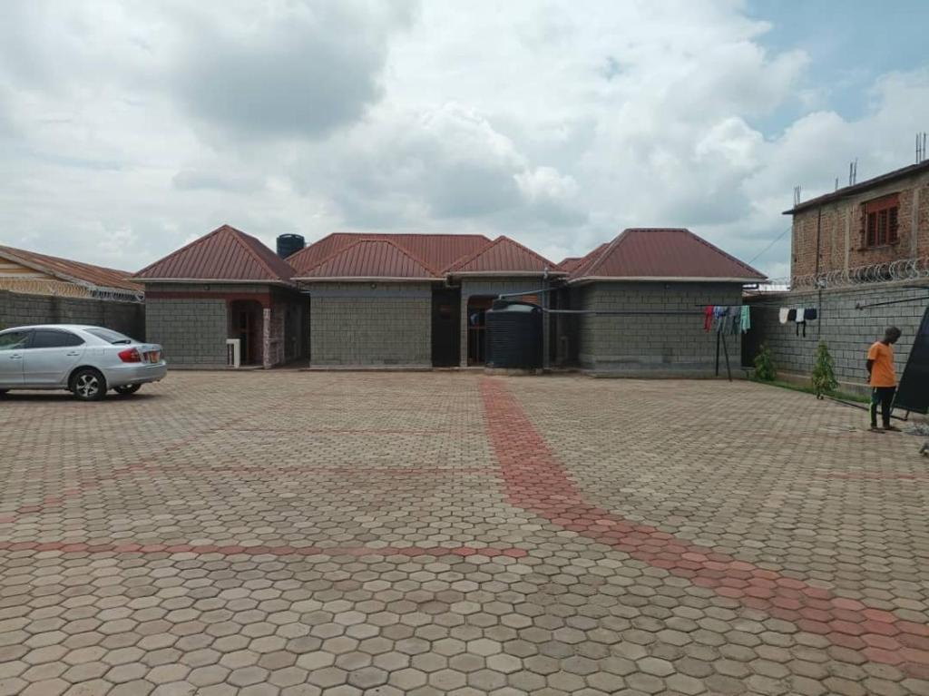 a brick parking lot with a car in front of some buildings at City Cottages Mbale in Mbale