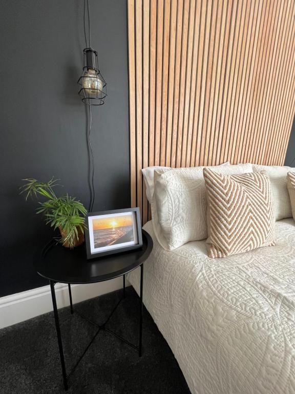 a table next to a bed with a laptop on it at Modern 2 bedroom beach house in Cleethorpes