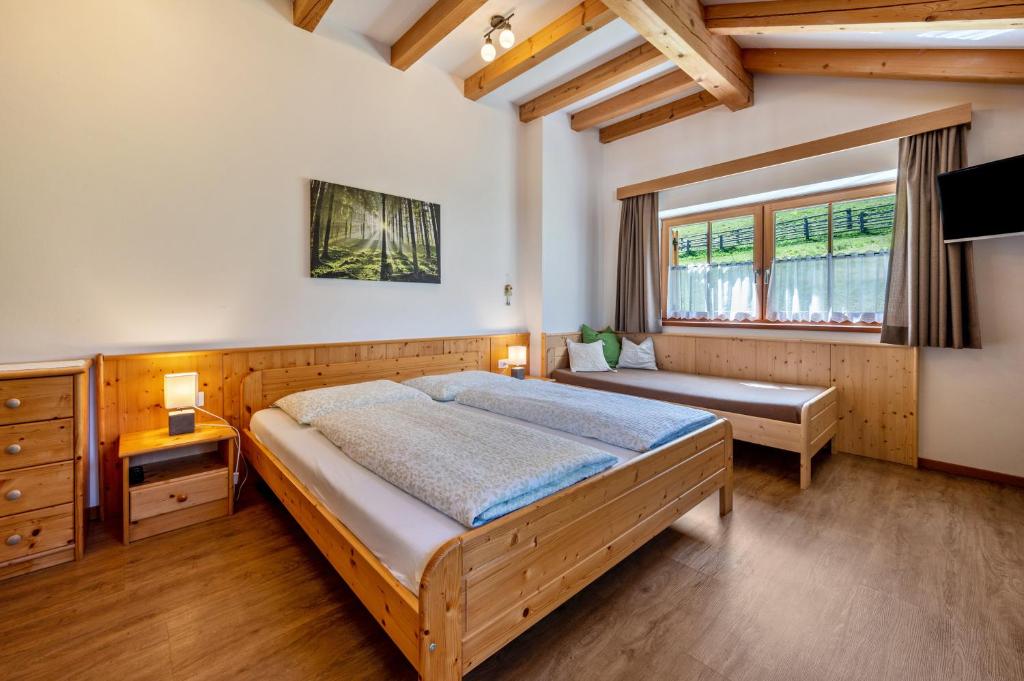 a bedroom with a large bed and a window at Urthalerhof Apt Landhaus in Valdaora