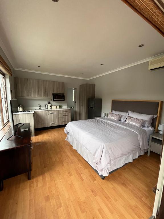 a bedroom with a large white bed and a kitchen at The Three Trees in Gillitts