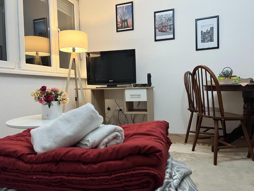 uma sala de estar com uma mesa com uma televisão e um cobertor vermelho em Apartman CENTAR em Zenica