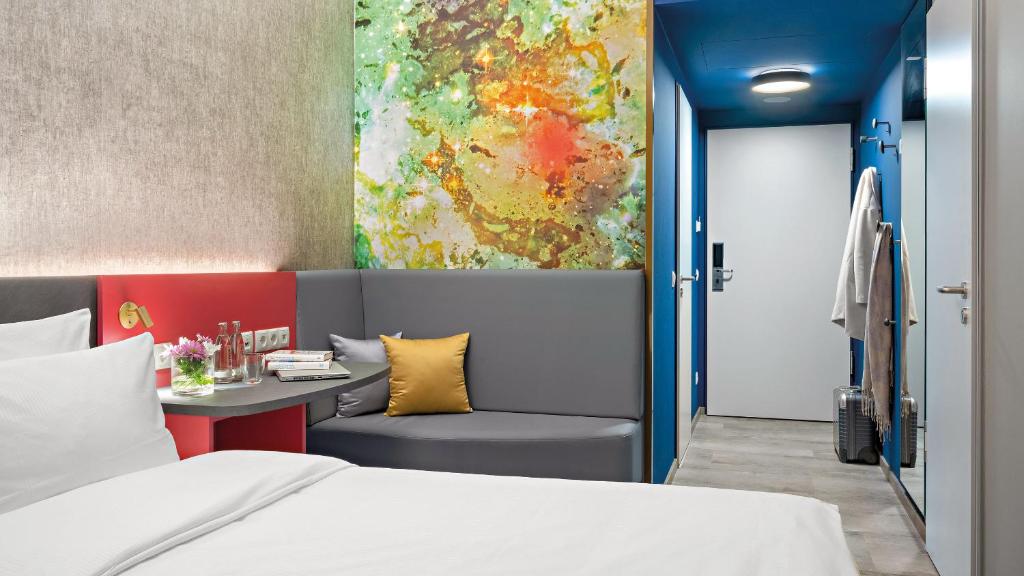 Un dormitorio con una cama y un escritorio con una pintura en Hey Lou Hotel Nördlingen en Nördlingen