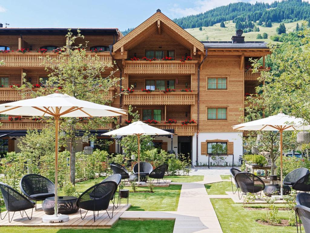 um hotel com mesas, cadeiras e guarda-sóis em Der Unterschwarzachhof em Saalbach-Hinterglemm