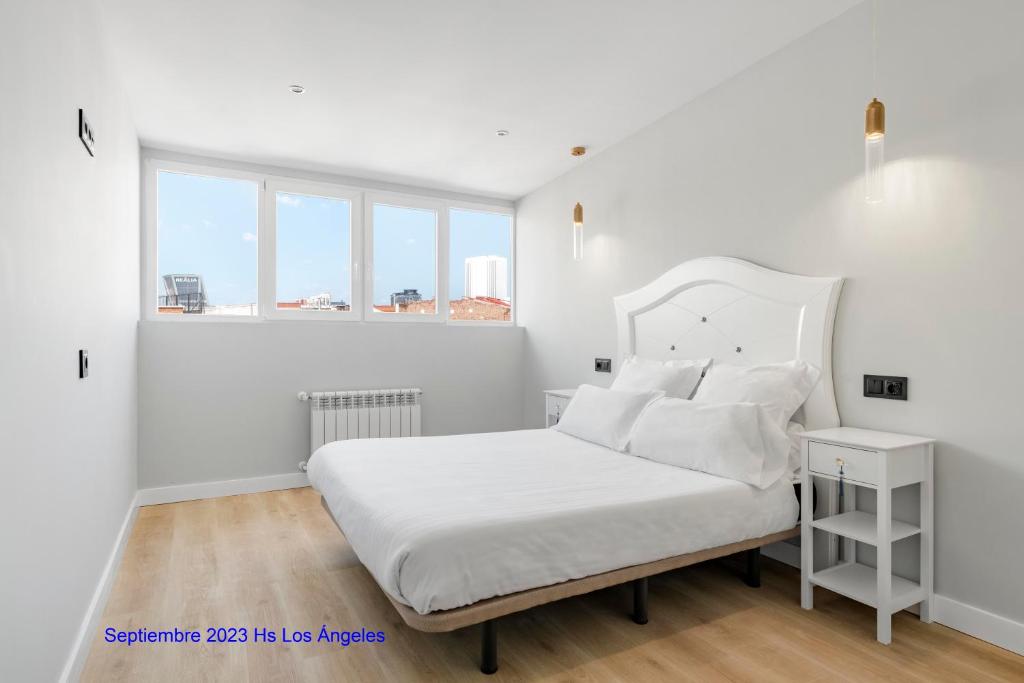 Dormitorio blanco con cama con sábanas y almohadas blancas en Hostal Los Ángeles, en Madrid