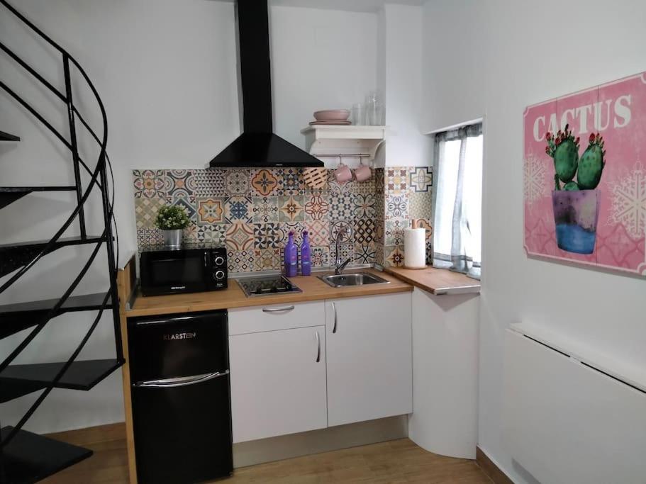 a kitchen with white cabinets and a black refrigerator at CASITA PINYPON in Jerez de la Frontera