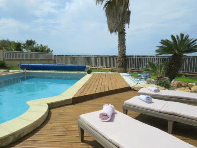 a swimming pool with two chaise lounges on a wooden deck at Villa piscine privée superbe Vue Etang Leucate 8JBART580 in Port Leucate