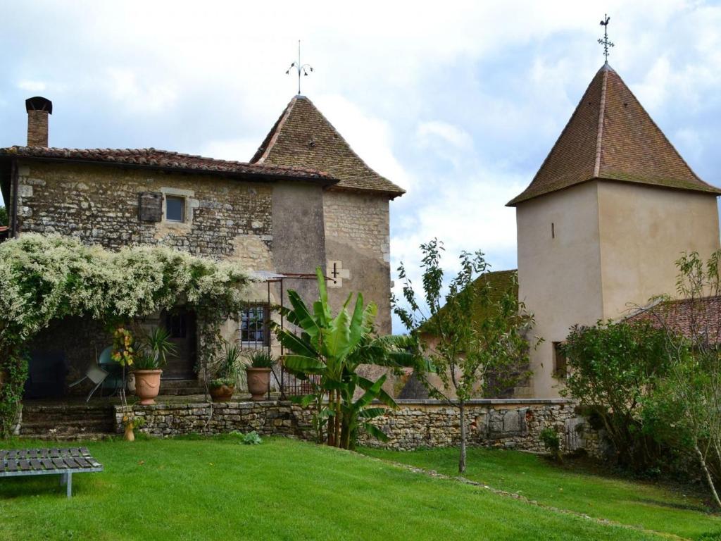 una casa antigua con una torre y un patio de césped en Gîte Beaulieu-sur-Sonnette, 2 pièces, 2 personnes - FR-1-653-219, en Beaulieu-sur-Sonnette