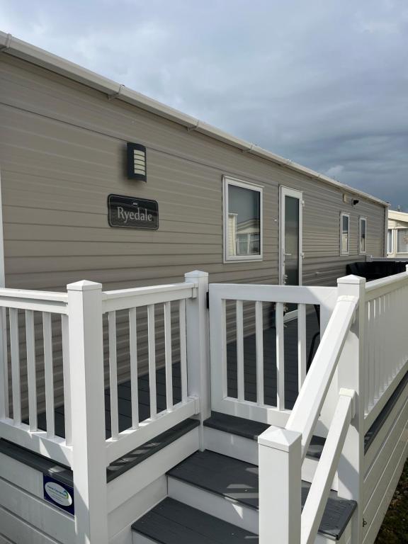 a mobile home with a porch and a white fence at Rydale in Whitstable