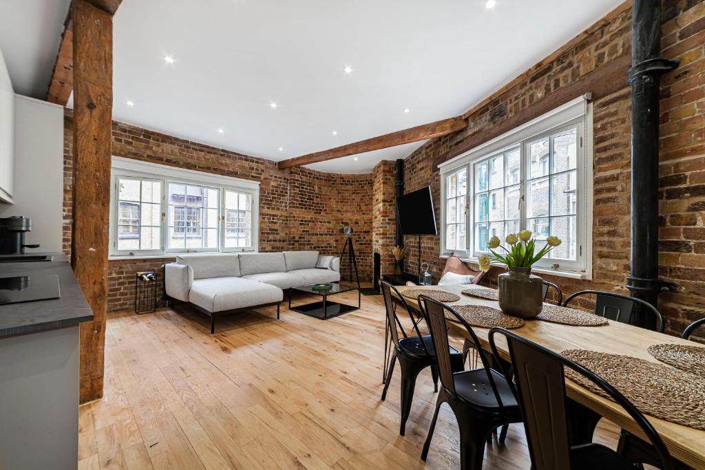 a living room with a couch and a table with chairs at Newly Refurbished Warehouse Cnv 2BR Apt Bermondsey in London