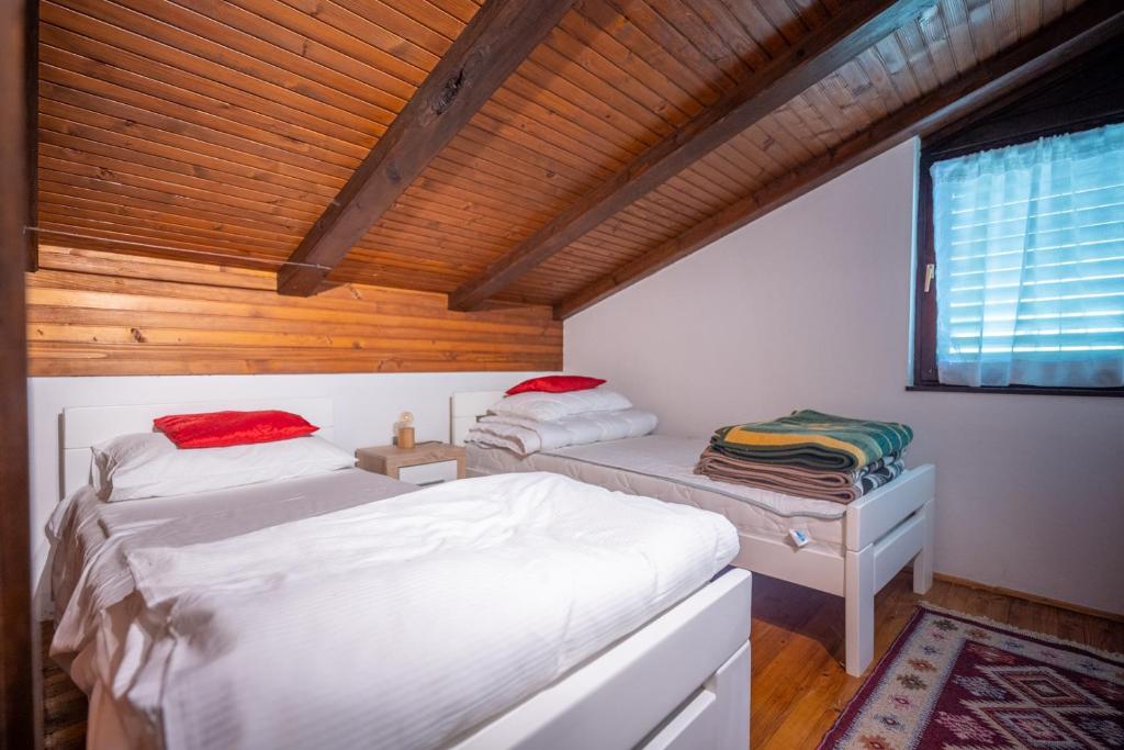 a bedroom with two beds and a wooden ceiling at Svjetlost in Jahorina