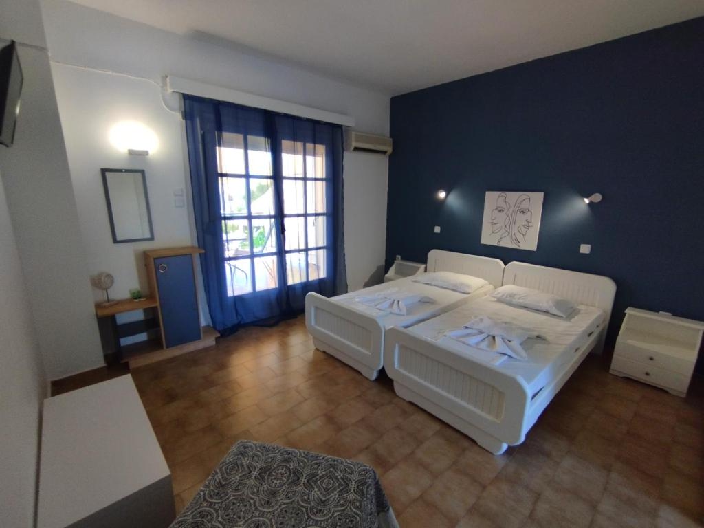 een slaapkamer met 2 bedden en een blauwe muur bij Spasmata Apartments no cooking in Minia