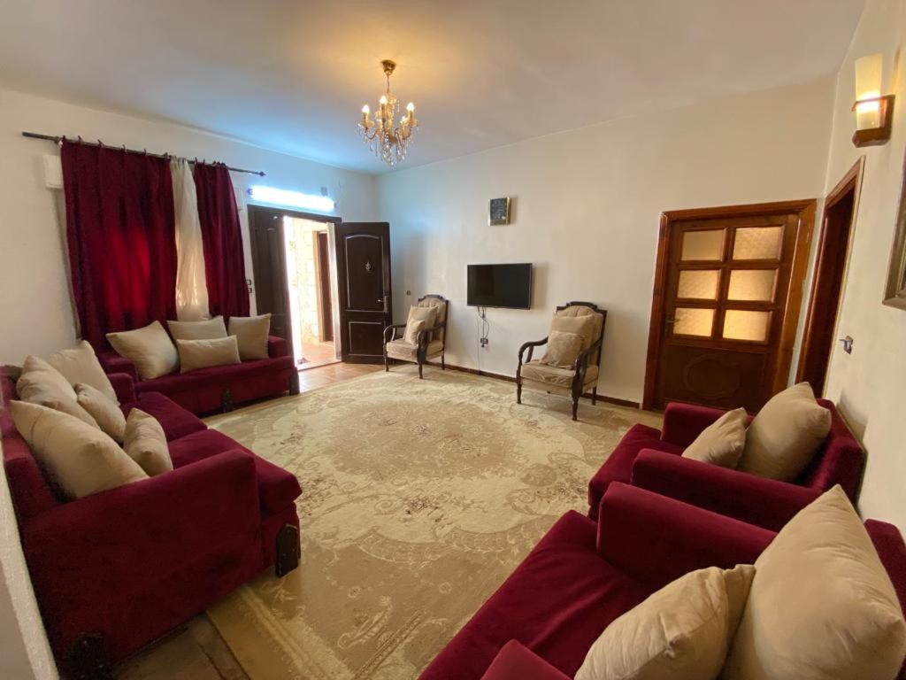 a living room with red couches and a television at Full furnitured house بيت مفروش للأيجار in Sūf