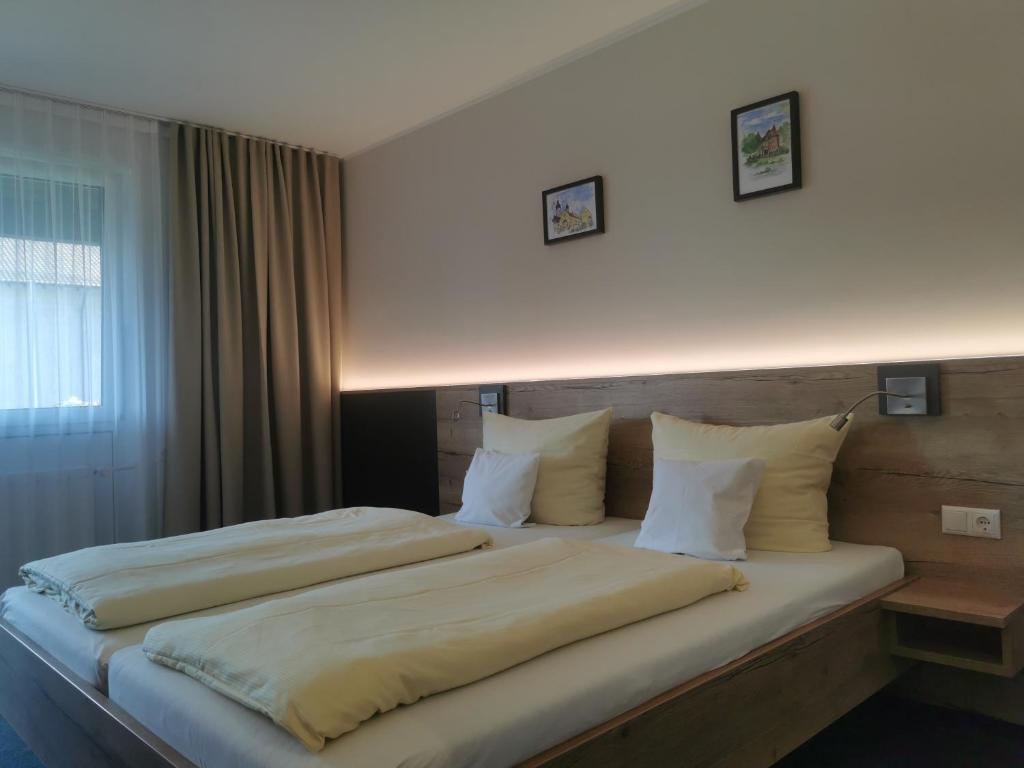 a bedroom with a large bed with white sheets and pillows at Hotel am Regenbogen in Cham