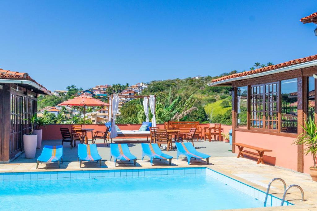 a swimming pool with chairs and tables and a patio at Pousada dos Coqueiros Búzios in Búzios