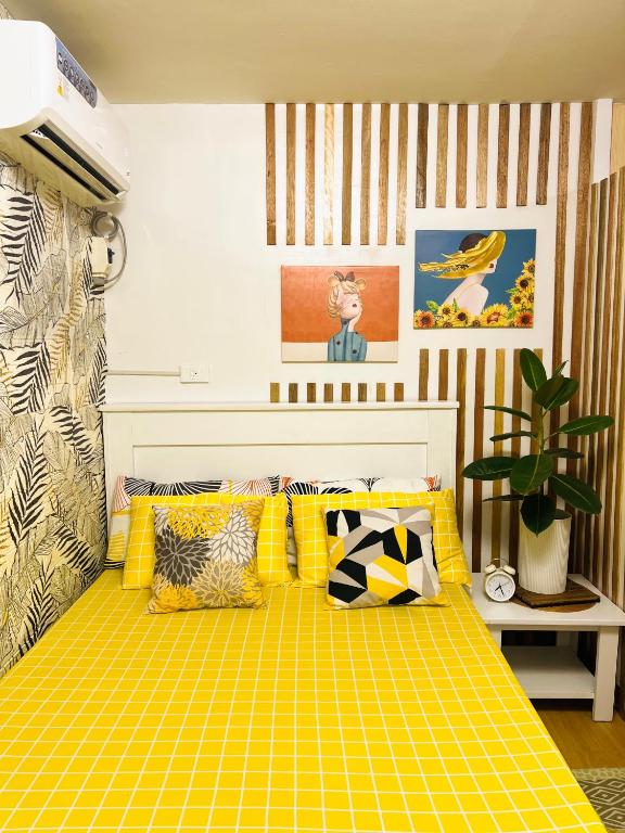 una cama amarilla con almohadas en una habitación en Bulacan Staycation At Urban Deca Homes Marilao en Marilao