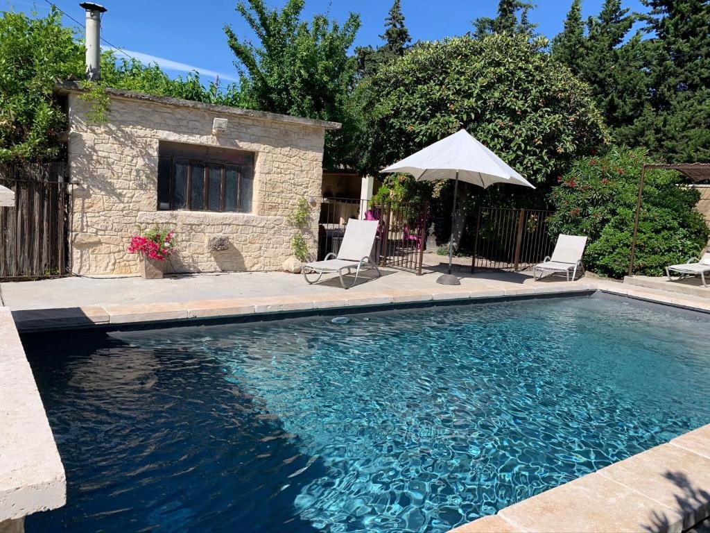 a swimming pool with two chairs and an umbrella at Superb holiday flat with private pool in Carpentras