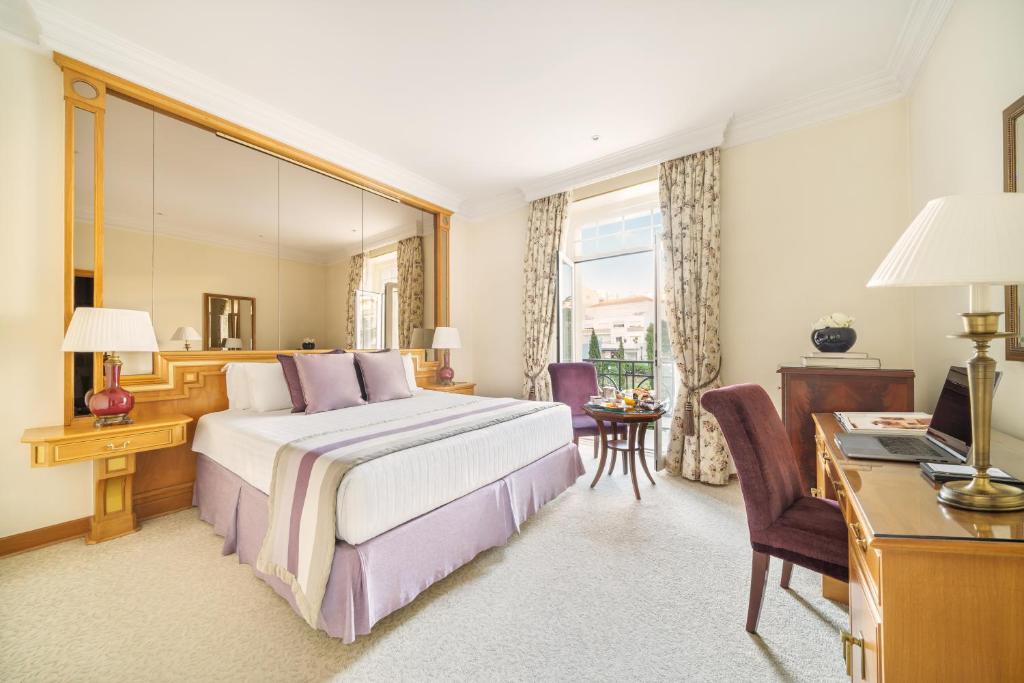 a hotel room with a bed and a desk and a computer at Palácio Estoril Hotel, Golf & Wellness in Cascais