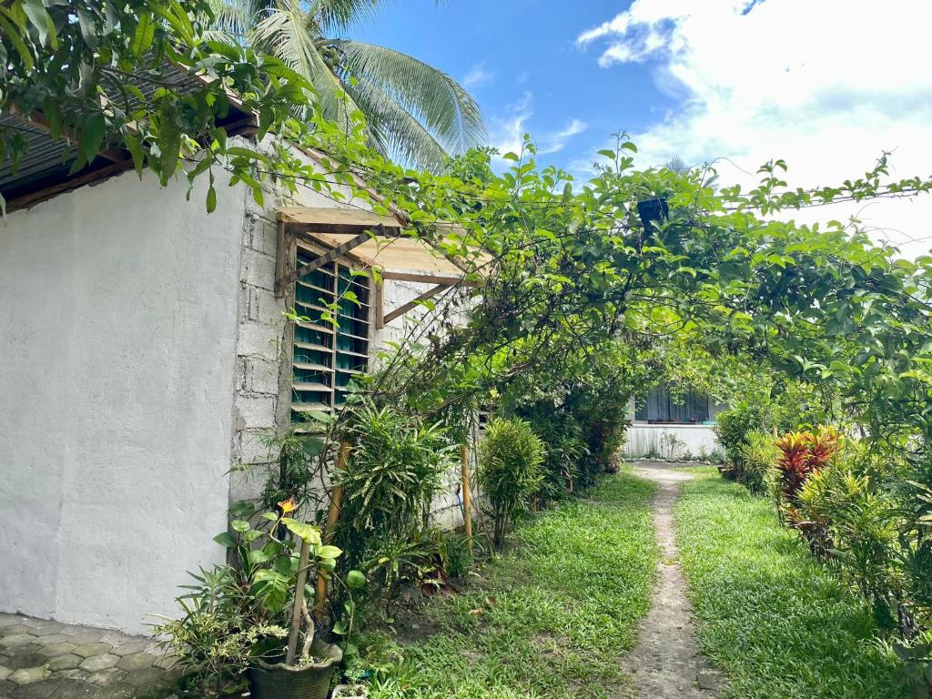 a garden with an arch of trees and plants at Punta Landing Travellers Inn in Surallah