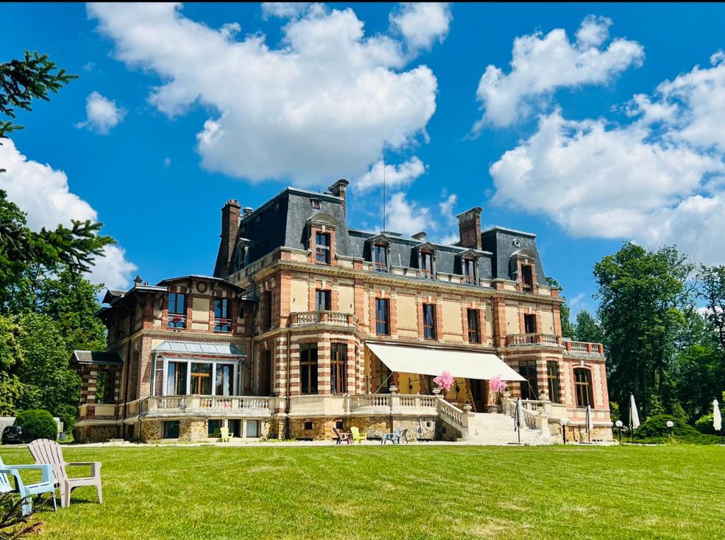 Château de Crènille في Chaumes-en-Brie: منزل كبير مع حقل عشبي أمامه