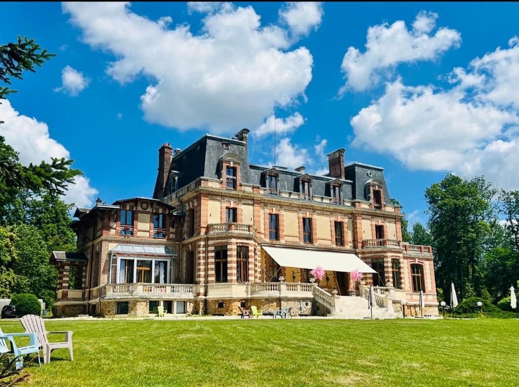 een groot huis met een grasveld ervoor bij Château de Crènille in Chaumes-en-Brie