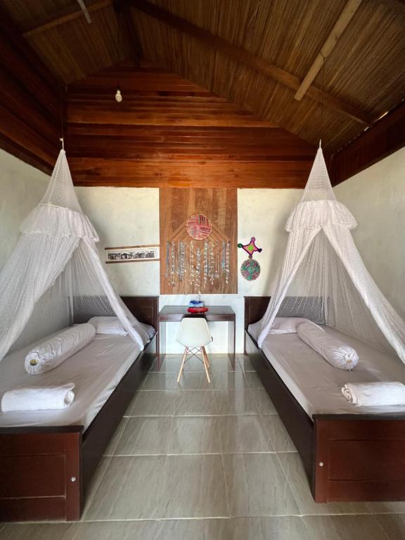 Duas camas com redes mosquiteiras num quarto em Mangkombong Homestay em Tapokreng