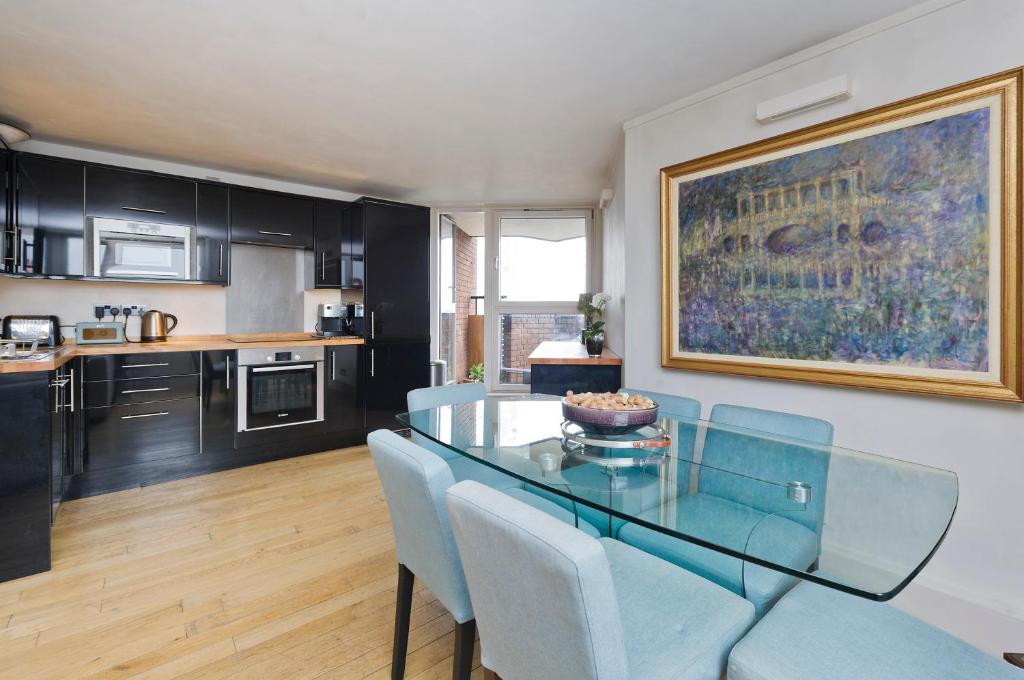 a dining room with a glass table and blue chairs at ALTIDO Charming flat overlooking River Thames in London