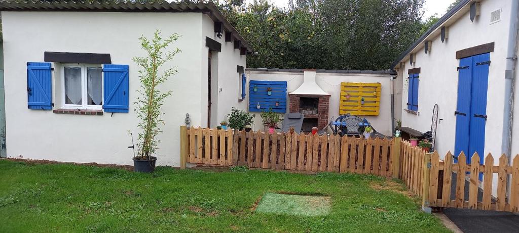 a house with blue windows and a wooden fence at Studio "l'aube du Perche" in La Mancelière