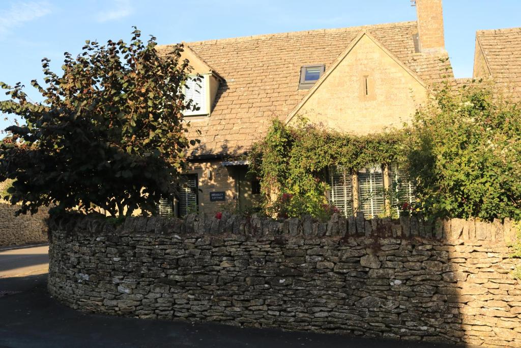 a stone retaining wall in front of a house at Beautiful Cottage in the Heart of Stow on the Wold in Stow on the Wold