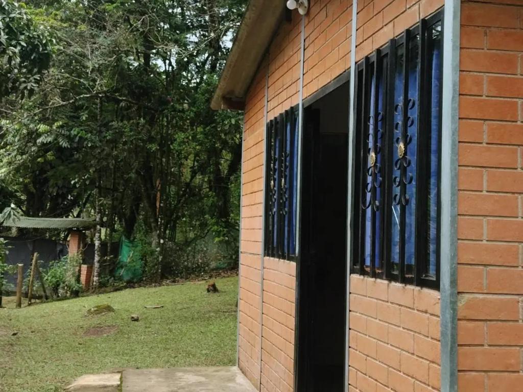 a brick building with blue windows on the side of it at Sapiens house"la Gallita de roca" in Cali