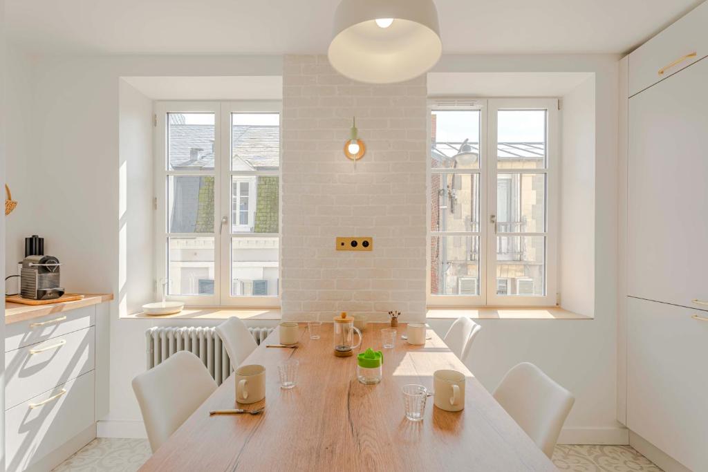Una cocina y un comedor con mesa y sillas de madera. en Neptune, en Trouville-sur-Mer