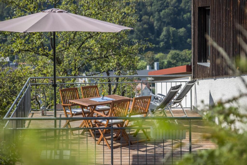 a table and chairs with an umbrella on a deck at Ferienwohnung Am Samuelstein in Bad Urach