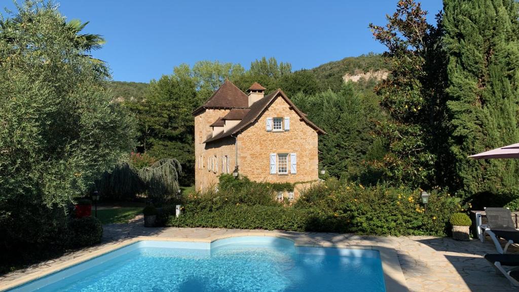 uma casa com uma piscina em frente em Le Moulin du Boisset em Saint-Denis-lès-Martel