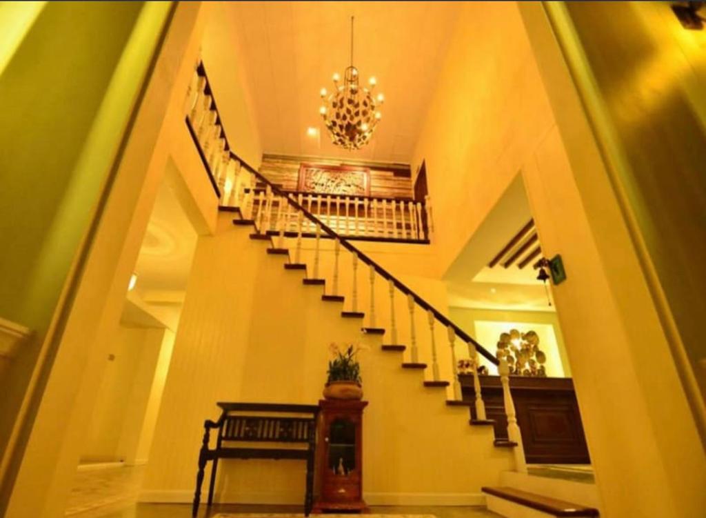 a spiral staircase in a house with a chandelier at Khummuangmin Boutique Hotel Nan in Nan