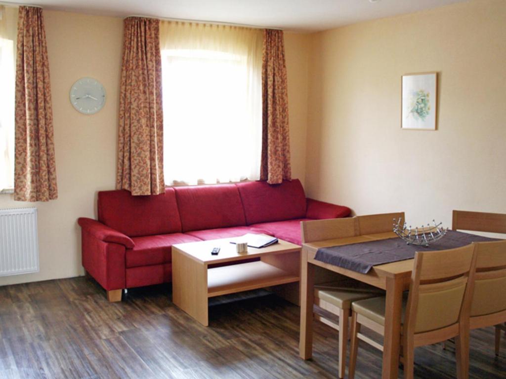 a living room with a red couch and a table at Kirschblüte in Colmberg