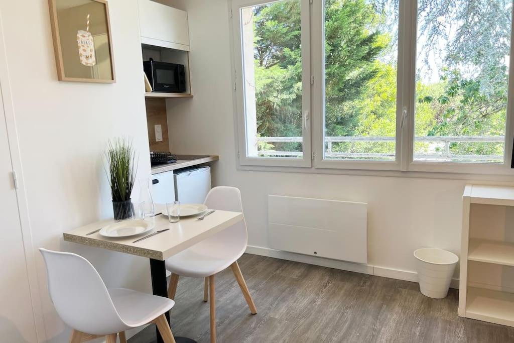 a kitchen with a white table and chairs and a window at Studio 1 Ananas cosy proche plages et commerces in Saint-Nazaire
