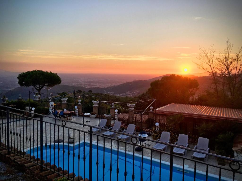 a pool with chairs and the sunset in the background at Isola Verde in Durazzano
