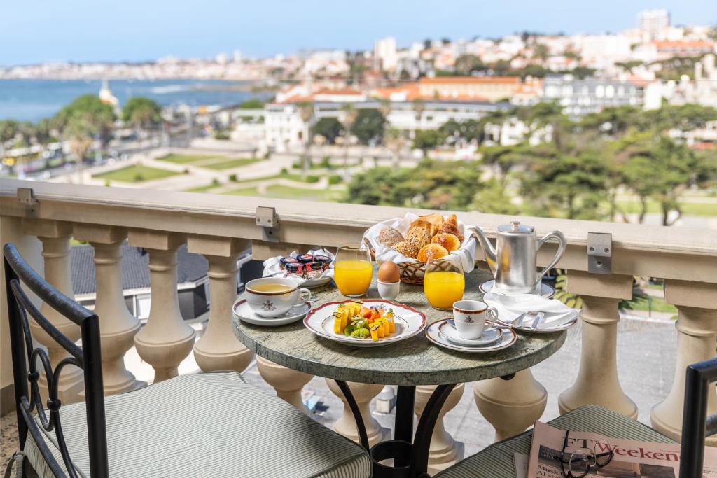 a table with breakfast food and orange juice on a balcony at Palácio Estoril Hotel, Golf & Wellness in Cascais