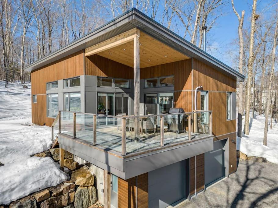 a house with a deck in the snow at Le Gaïa - Chalet en nature in Quebec City