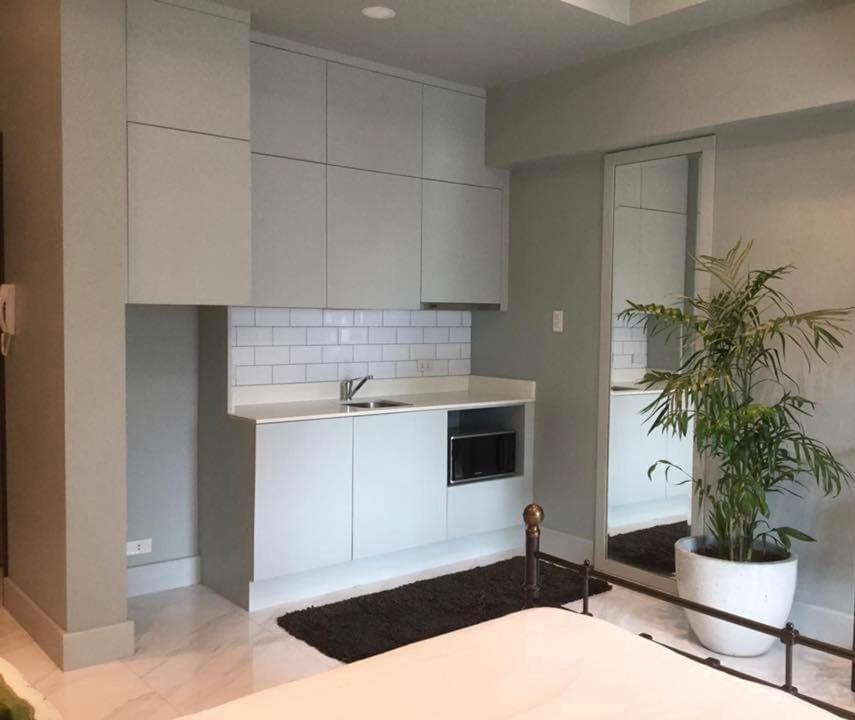 a kitchen with white cabinets and a potted plant at Condo Hotel at Greenbelt makati with cityview in Manila