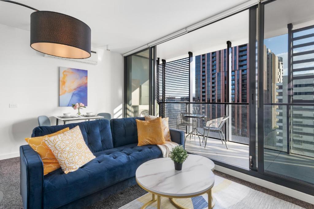 een woonkamer met een blauwe bank en een tafel bij Cozy & Romantic 1 Bedroom Apt in Southbank with Pool & Gym in Melbourne