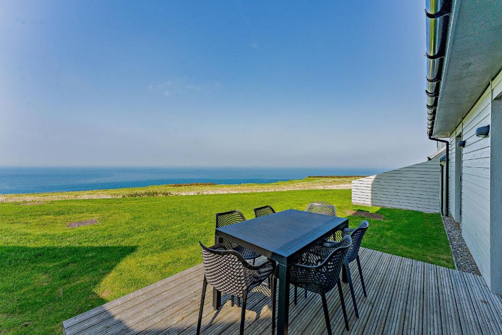 a table and chairs on a deck with the ocean at 18 - 3 Bedroom Cottage - LP in Pwllheli