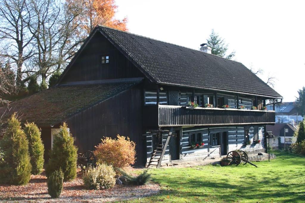 een zwarte schuur met een zwart dak bij Quiet and charming log farmhouse in Libošovice