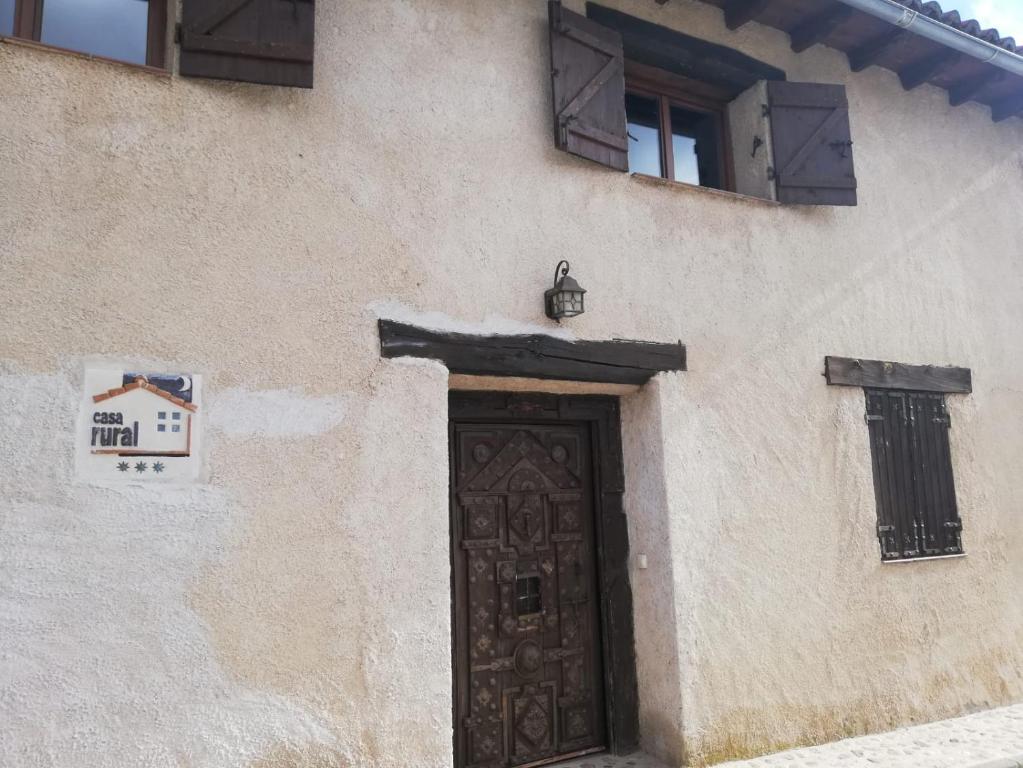 un edificio con una puerta marrón y dos ventanas en LA FRAGUA - CASA RURAL EN VILLANUEVA DE GOMEZ (AVILA), en Villanueva de Gómez