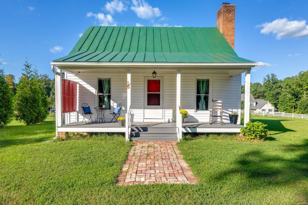 een klein wit huis met een groen dak bij Tranquil Cottage in Virginia Countryside with Pond! in Midlothian
