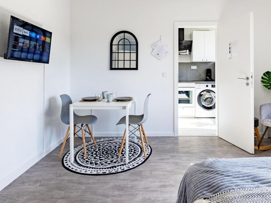 Habitación blanca con mesa y 2 sillas en # VAZ Apartments E01 Küche, TV, Netflix, ca 15 Min Messe u HBf, en Essen