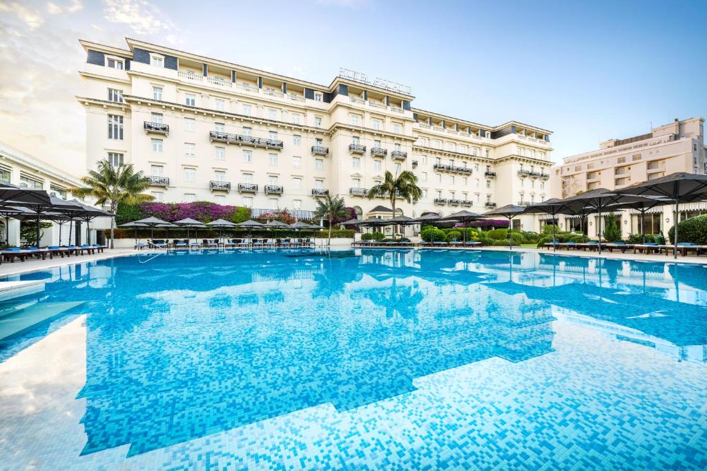 a large swimming pool in front of a building at Palácio Estoril Hotel, Golf & Wellness in Cascais