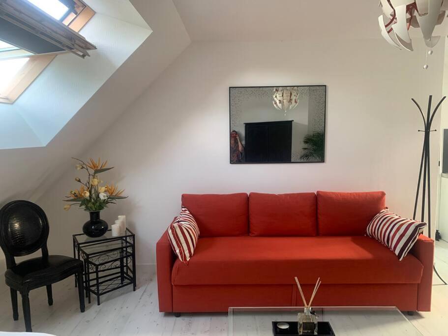 un sofá rojo en la sala de estar con espejo en Studio rénové tout confort, en Donnery